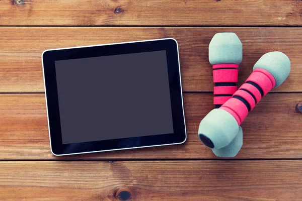 Close up of dumbbells and tablet pc on wood — Stock Photo, Image