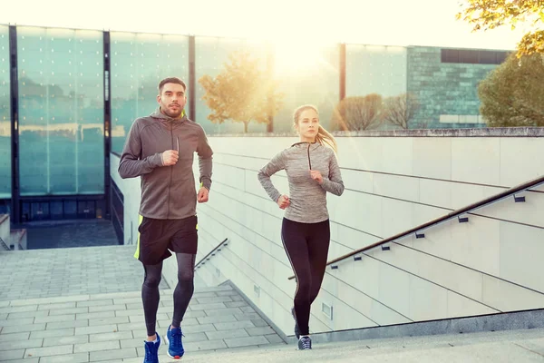 Happy couple running upstairs on city stairs — Stock Photo, Image