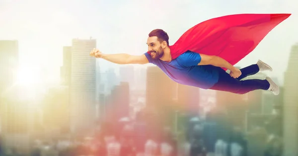 Homem feliz em capa de super-herói vermelho voando no ar — Fotografia de Stock
