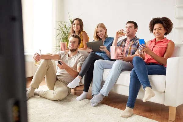 Friends with gadgets and beer watching tv at home — Stock Photo, Image