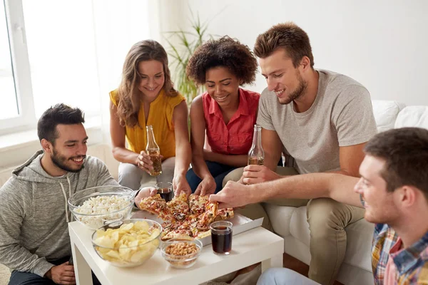 Amici felici con bevande mangiare pizza a casa — Foto Stock