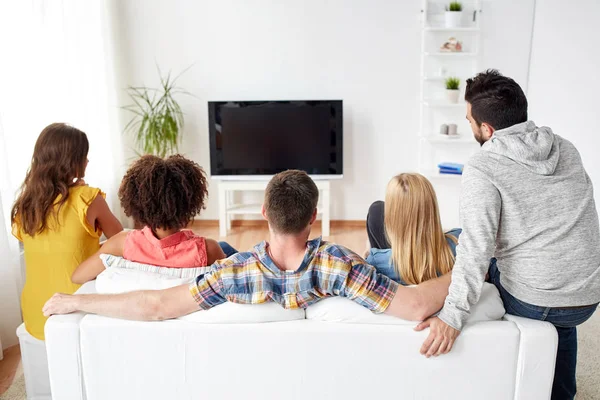 Amigos felizes assistindo tv em casa — Fotografia de Stock