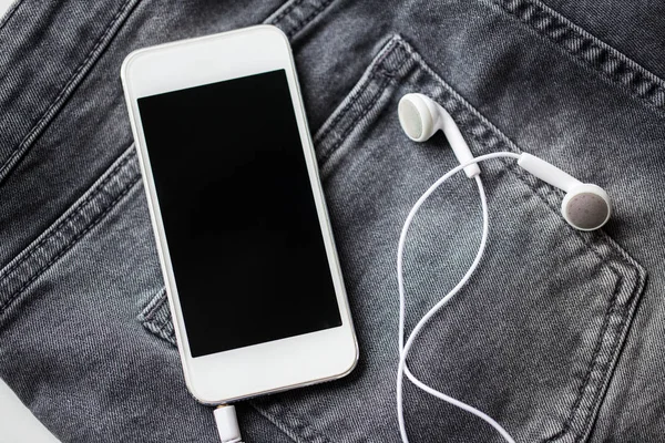 Smartphone and earphones on denim or jeans pocket — Stock Photo, Image