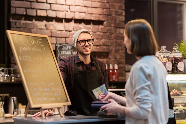 Happy barman and woman paying money at cafe — Stock Photo, Image