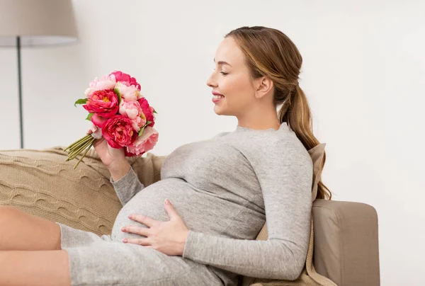 Glücklich schwangere Frau mit Blumen zu Hause — Stockfoto