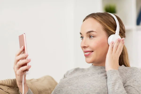 Mujer con smartphone y auriculares en casa —  Fotos de Stock