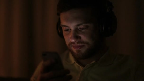 Muž s smartphone a sluchátky v noci — Stock video