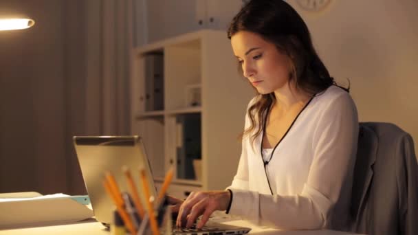 Mujer cansada escribiendo en el ordenador portátil en la oficina de noche — Vídeos de Stock