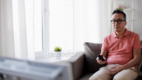 Homme avec télécommande regardant la télévision à la maison — Video