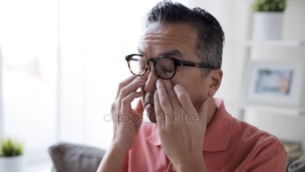 Hombre cansado en gafas frotando los ojos en casa — Vídeo de stock