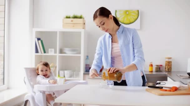 Madre cocinando comida y alimentando al bebé en casa — Vídeos de Stock