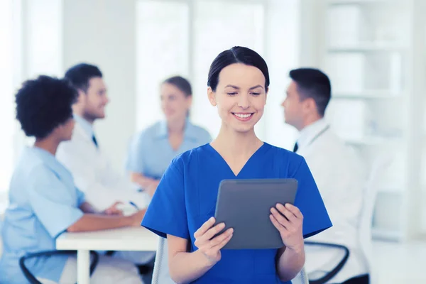 Glada läkare med TabletPC över laget på klinik — Stockfoto