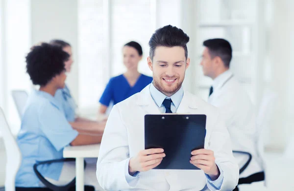 Happy doctor with tablet pc over team at clinic — Stock Photo, Image