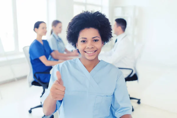 Happy female doctor or nurse showing thumbs up — Stock Photo, Image