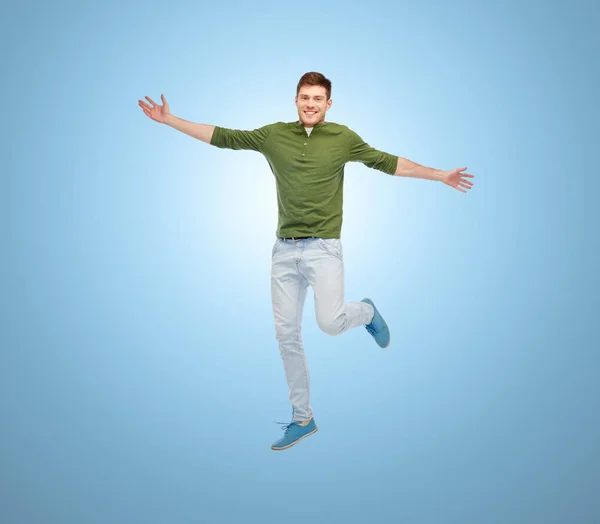Улыбающийся молодой человек, прыгающий в воздух — стоковое фото