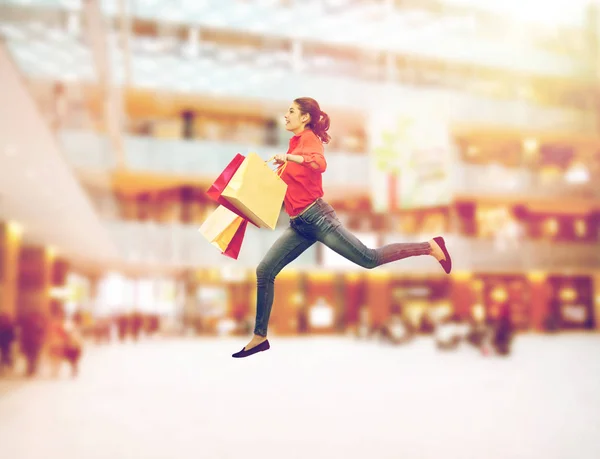 Усміхнена молода жінка з сумками стрибає — стокове фото