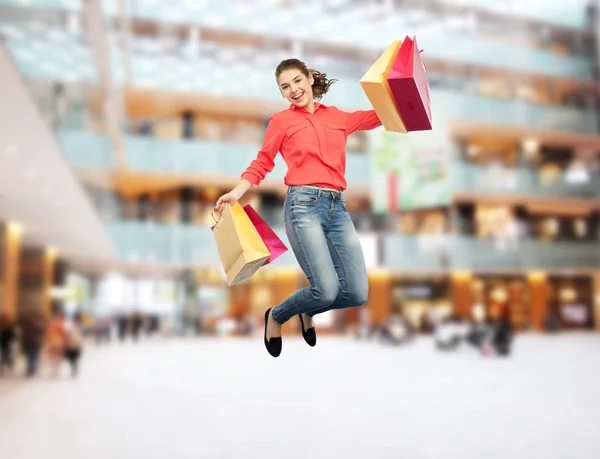 Sorridente giovane donna con shopping bags jumping — Foto Stock