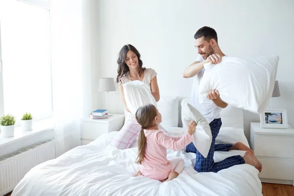 Famille heureuse ayant bataille d'oreillers dans le lit à la maison — Photo