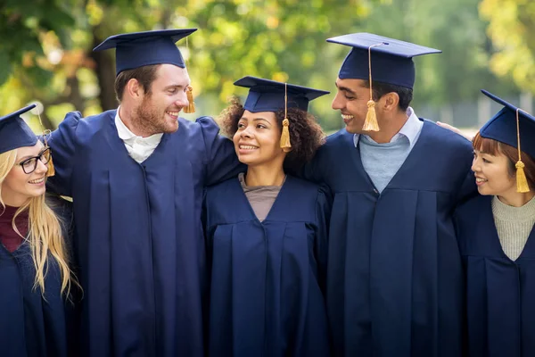 Happy students or bachelors in mortar boards — Stock Photo, Image