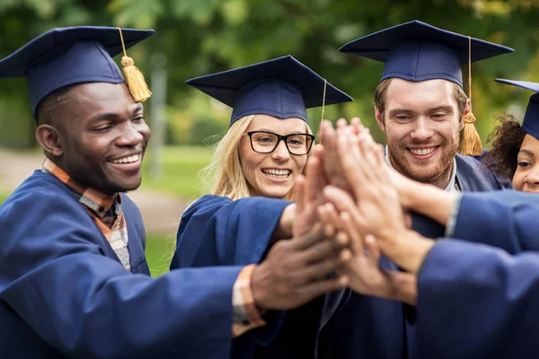 Estudiantes felices en tableros de mortero haciendo cinco — Foto de Stock