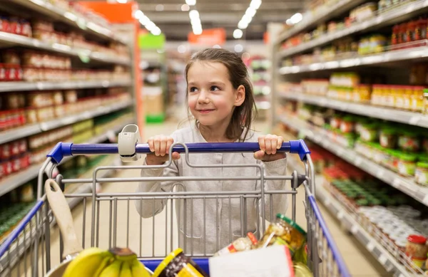 Menina com comida no carrinho de compras na mercearia — Fotografia de Stock