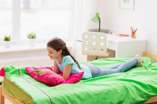 Smiling girl texting on smartphone at home — Stock Photo, Image