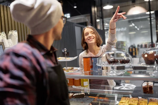 Gelukkige vrouw iets te tonen aan de barman in café — Stockfoto