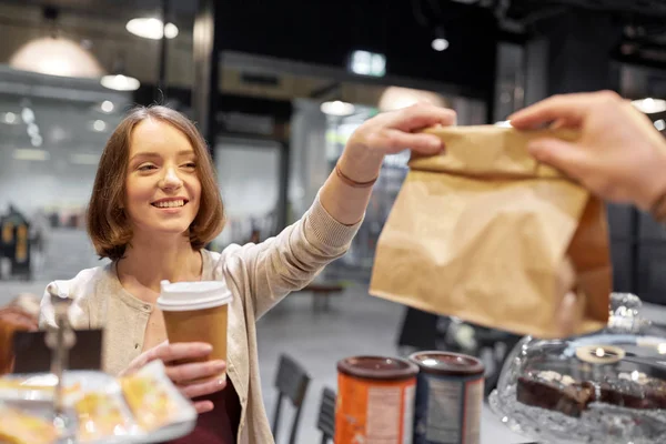 Vrouw neemt papieren zak van verkoper in cafe — Stockfoto