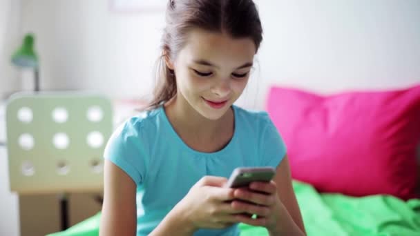 Gülümseyen kız evde akıllı telefondan mesaj atıyor. — Stok video