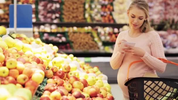 Mujer embarazada feliz comprando manzanas en el supermercado — Vídeos de Stock