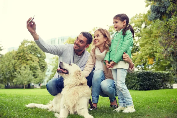Familia feliz con perro tomando selfie por teléfono inteligente —  Fotos de Stock