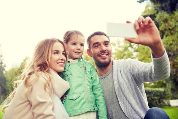 Familia feliz tomando selfie por teléfono inteligente al aire libre — Foto de Stock