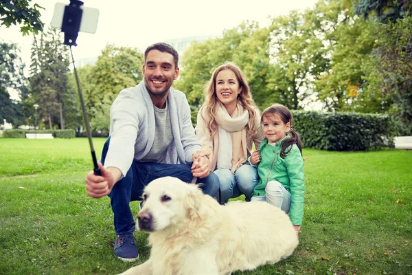 Familia feliz con perro tomando selfie por teléfono inteligente — Foto de Stock