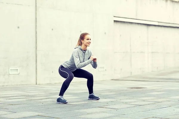 Mujer feliz haciendo sentadillas y haciendo ejercicio al aire libre — Foto de Stock