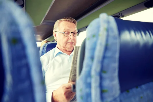 Homem sênior feliz lendo jornal em ônibus de viagem — Fotografia de Stock
