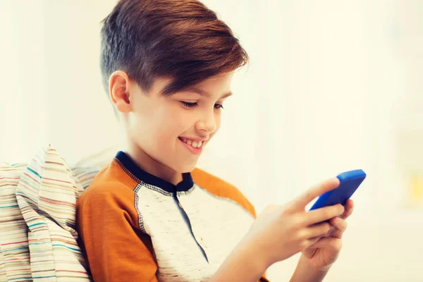 Мальчик со смартфоном смс или играть дома — стоковое фото