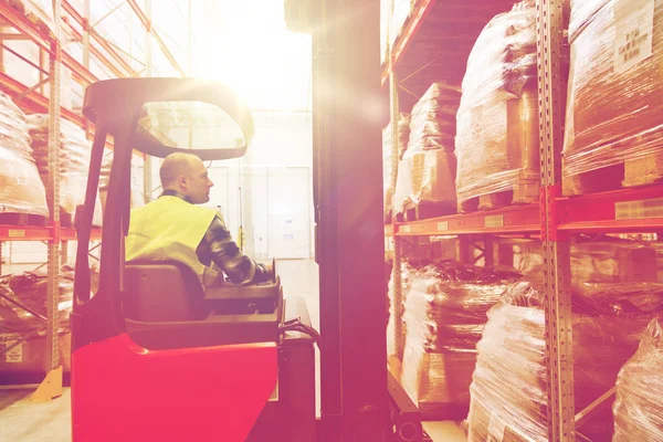 Man op de heftruck laden van vracht in magazijn — Stockfoto