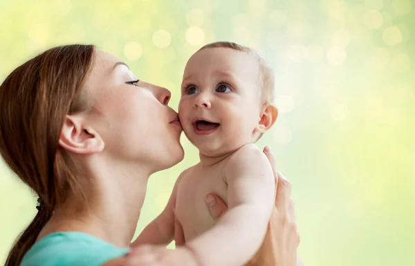 Счастливая молодая мать целует маленького ребенка — стоковое фото