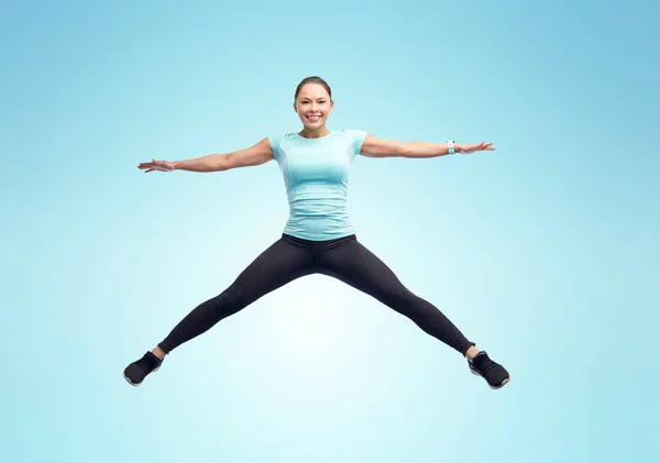 Gelukkig glimlachen sportieve jonge vrouw springen in de lucht — Stockfoto