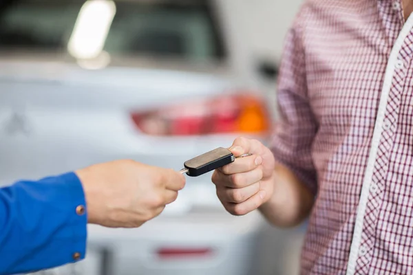 Auto mechanic giving car key to man at workshop — Stock Photo, Image