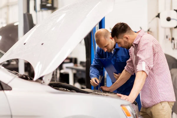 Auto monteur met klembord en man bij de auto-shop — Stockfoto