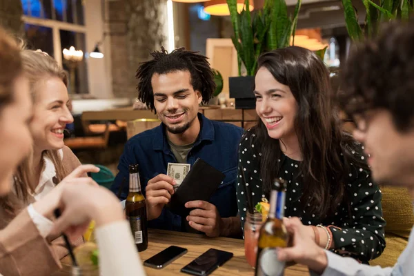 Vrienden met drankjes, geld en bill bij bar — Stockfoto