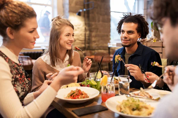 Amigos felizes comendo e bebendo no restaurante — Fotografia de Stock