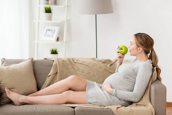 Happy pregnant woman eating green apple — Stock Photo, Image