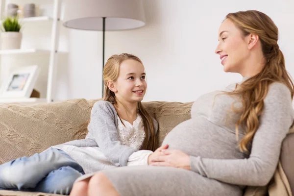 Gelukkig zwangere vrouw en meisje op de sofa thuis — Stockfoto