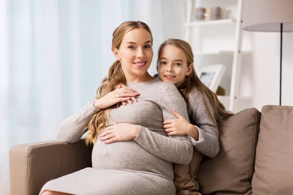 Boldog terhes nő és lány átölelve otthon — Stock Fotó