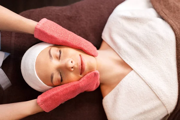 Kobieta mająca masaż twarzy z rękawiczkami frotte w spa — Zdjęcie stockowe
