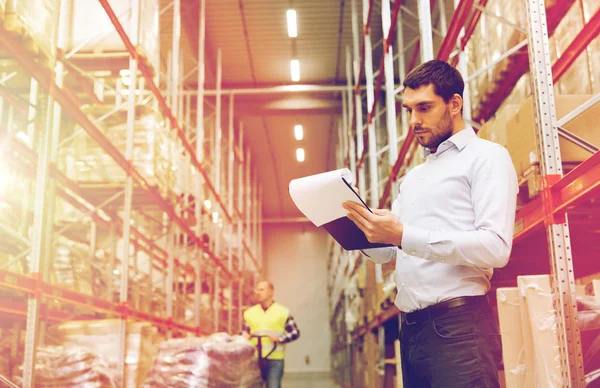 Hombre de negocios escribiendo al portapapeles en el almacén — Foto de Stock