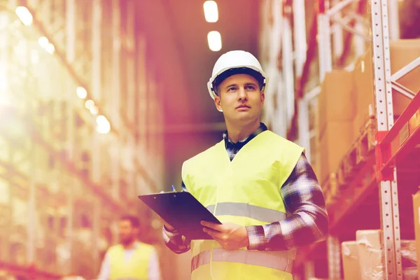 Man with clipboard in safety vest at warehouse — Stock Photo, Image