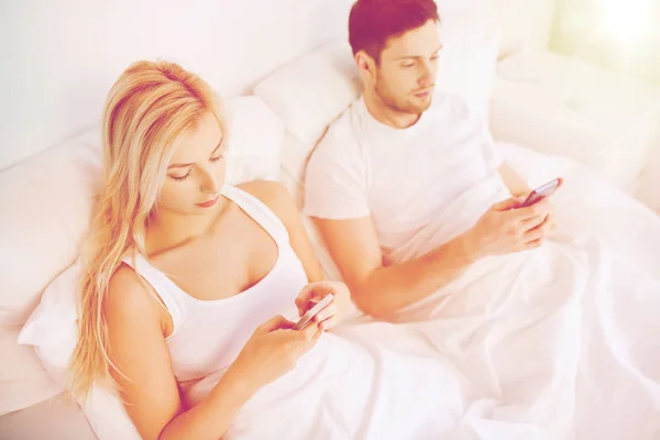 ベッドの上でスマートフォンを持つカップル — ストック写真